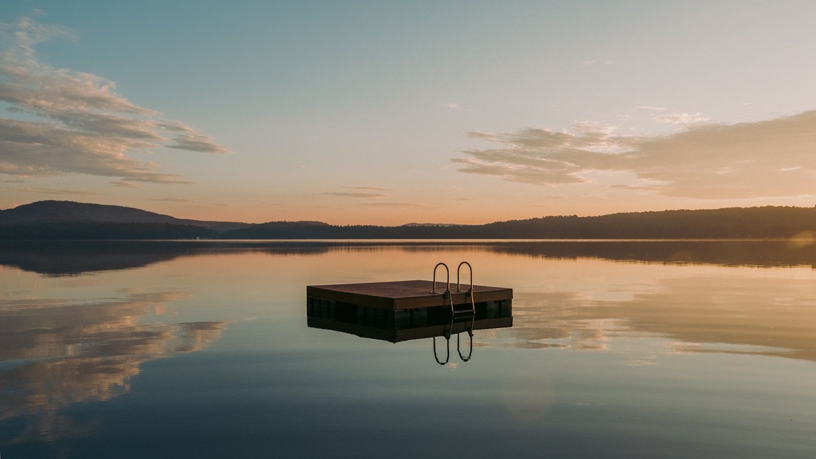 A wooden swim float on a calm lake at sunrise